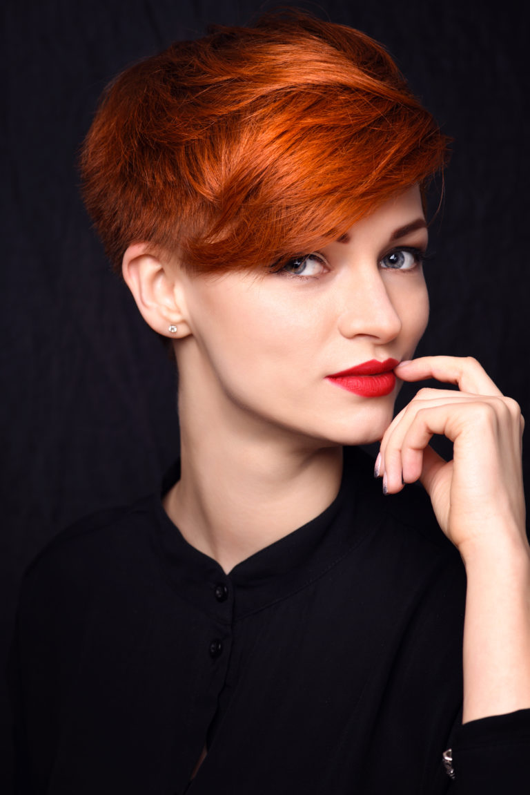 Portrait of a beautiful young red-haired woman with short hair on a dark background