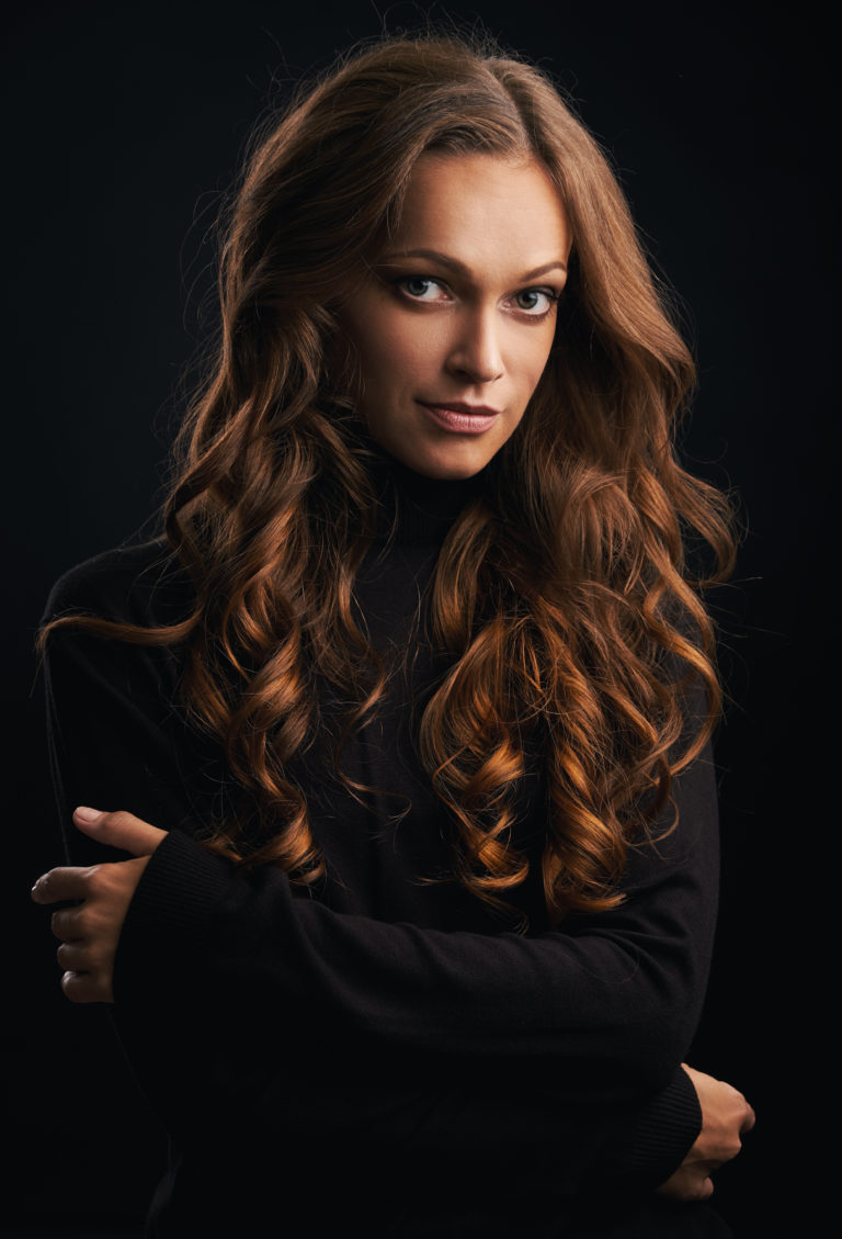 Brunette girl with long and shiny wavy hair. Beautiful model with curly hairstyle